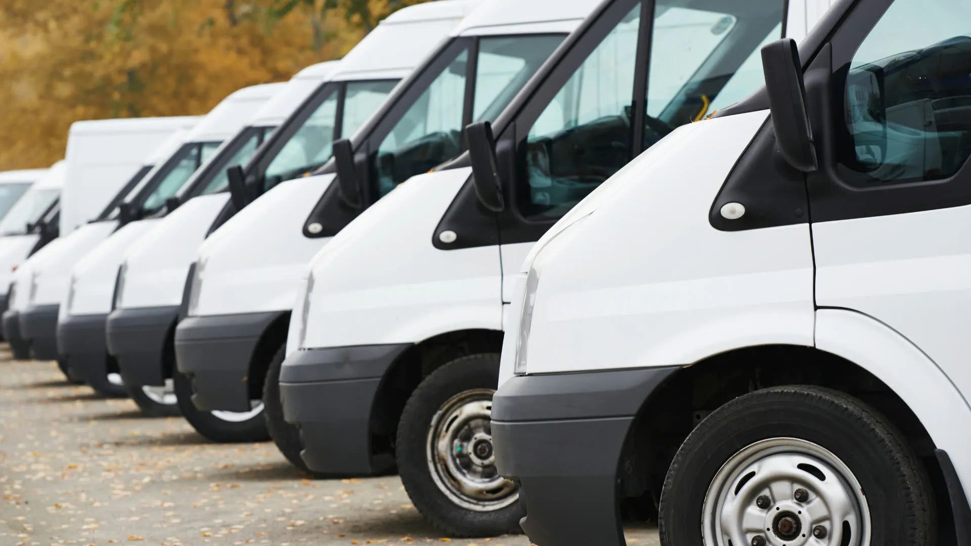 A row of white cargo vans parked side by side