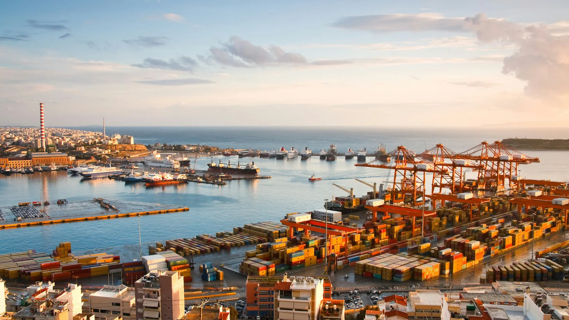 Aerial view of a container port with cranes and stacked containers in evening light