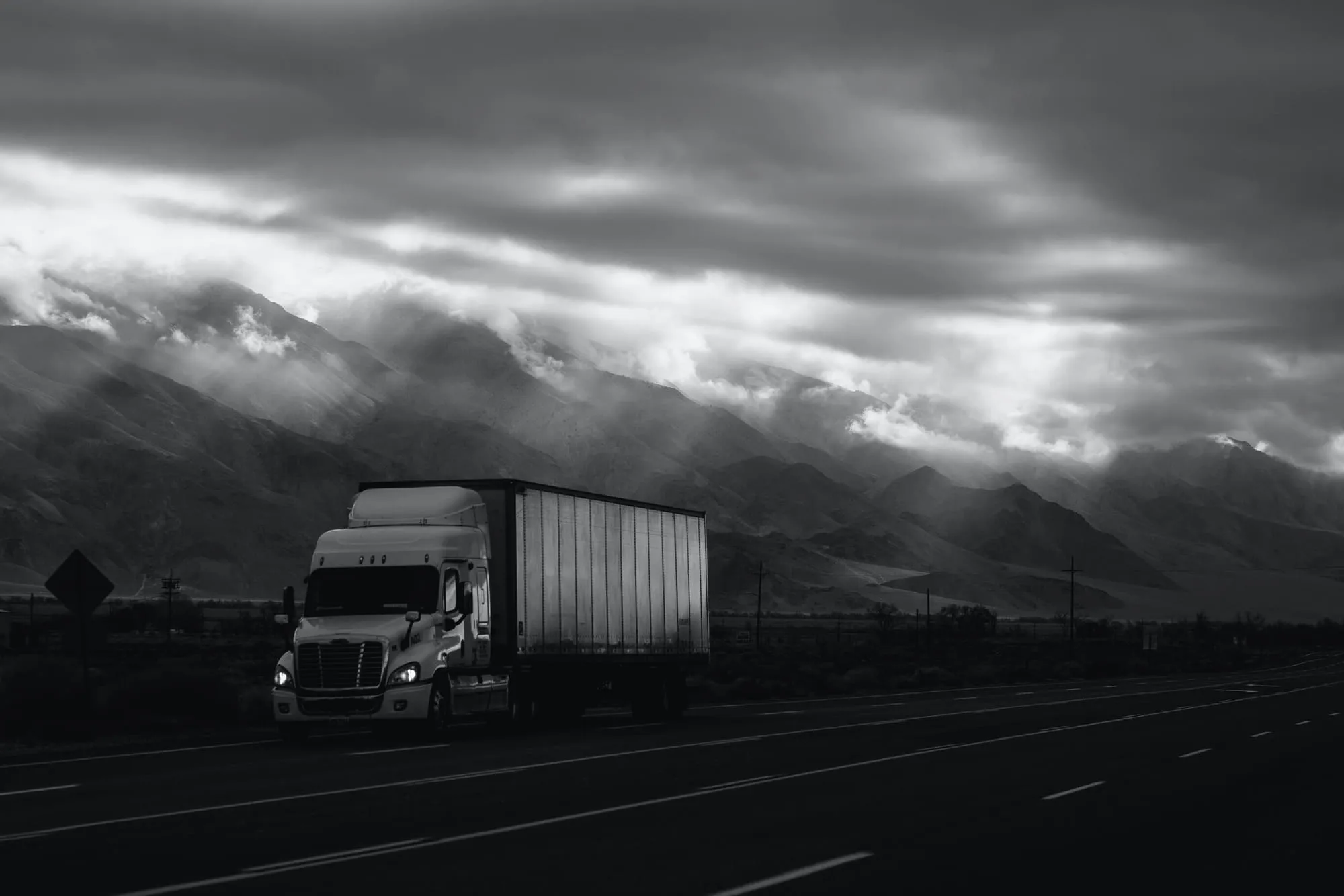 Semi truck on an open highway under a stormy sky