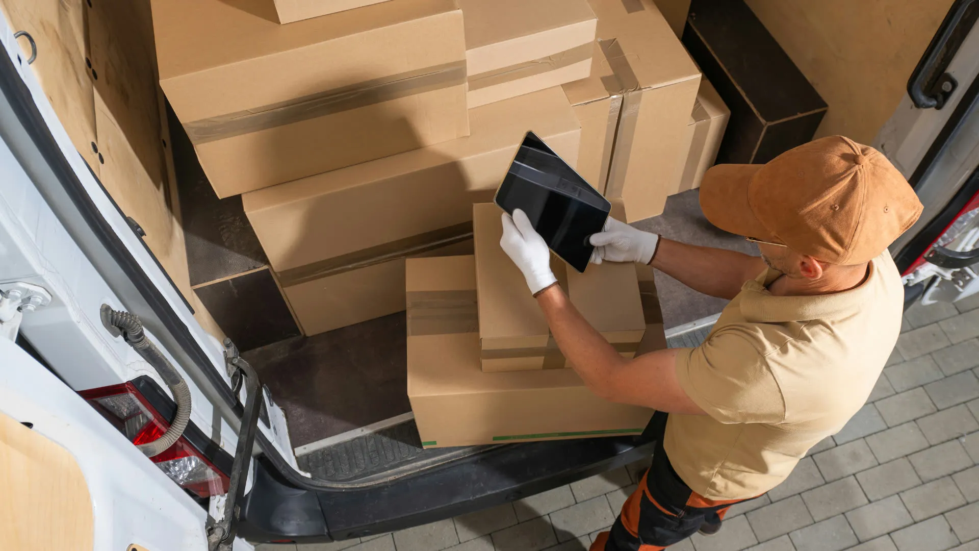 Driver with a tablet loading cardboard boxes into a cargo van